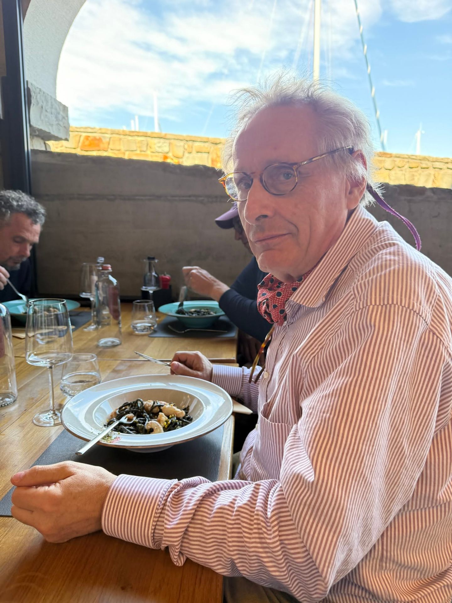 Pierre enjoying pasta at a Mediterranean waterfront restaurant.