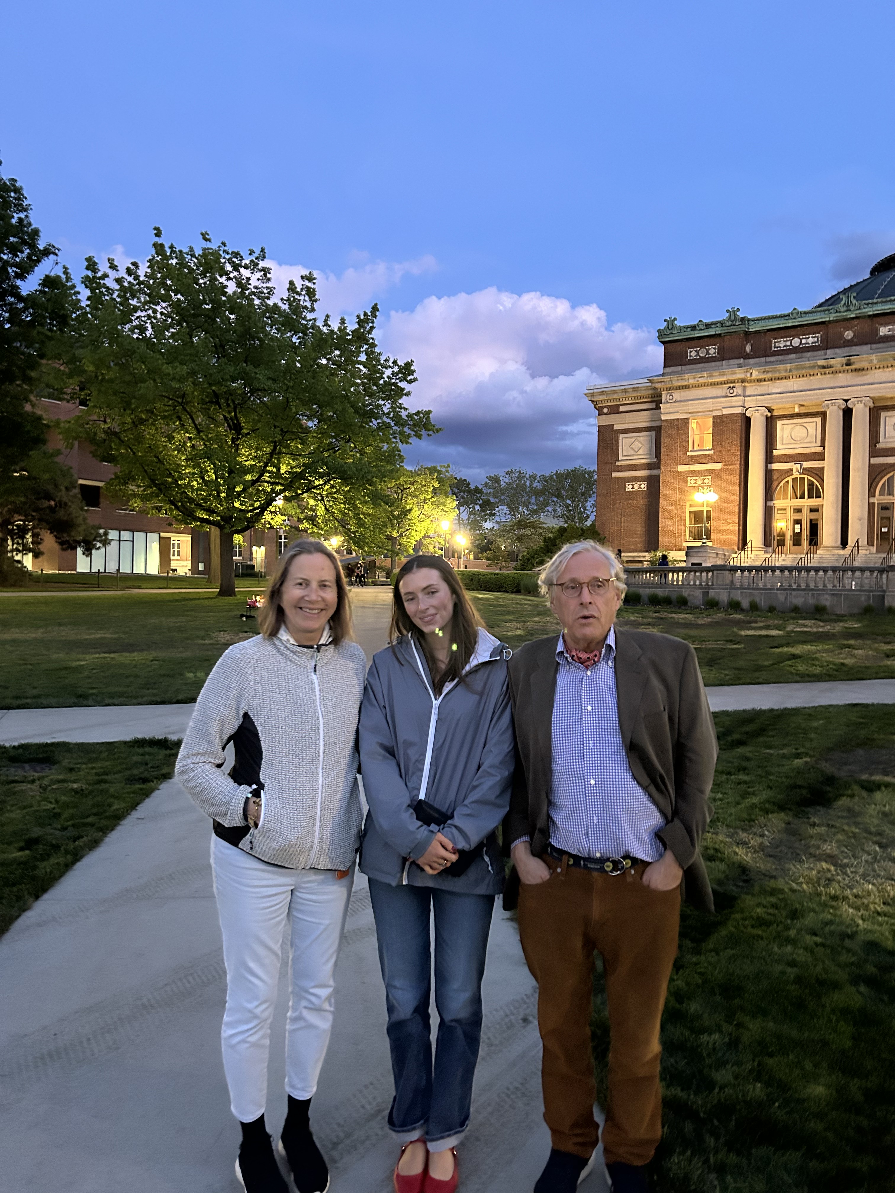 Pierre with family on a college campus at dusk.